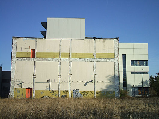 Brandwand an reduziertem Geb&auml;udekomplex vor einer Begr&uuml;nung